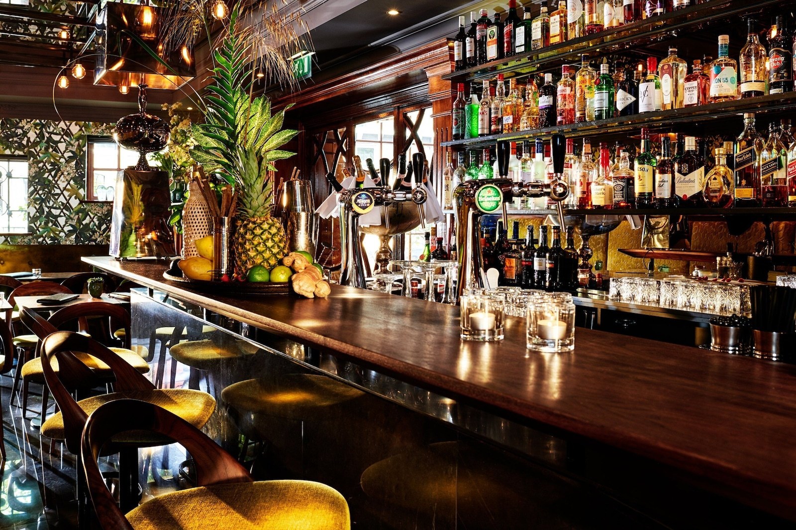 A bar with multiple liquor bottles, a pineapple, and a variety of bar tools. - Hotel Estheréa (Amsterdam)