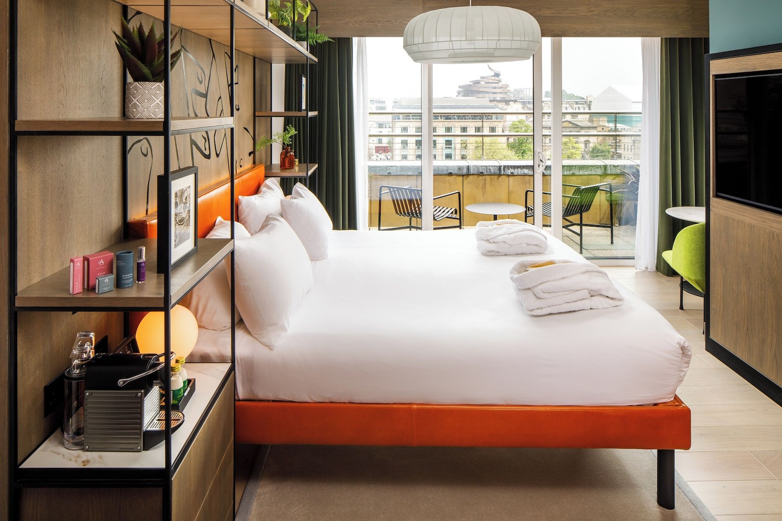 A modern hotel room with a large bed, a balcony with a view of the city, and a small table with chairs. - ibis Styles Edinburgh Centre St Andrew Square (Edinburgh)