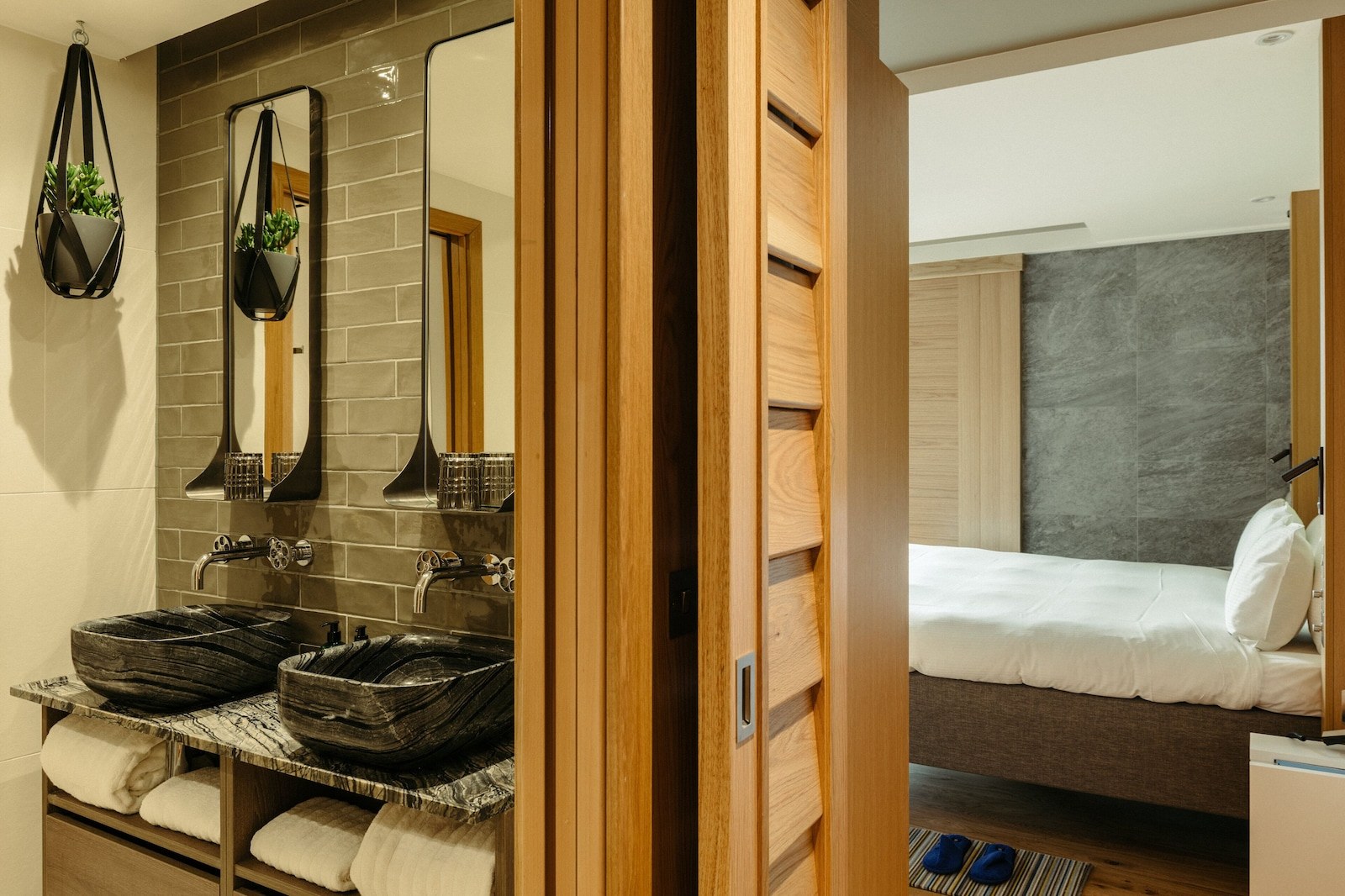 A bathroom with two large, dark stone sinks, a mirror, and a towel rack. - Market Street Hotel (Edinburgh)